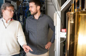 Mikhail Lukin (left) and Can Knaut stand near a quantum network node called a diamond silicon vacancy center.